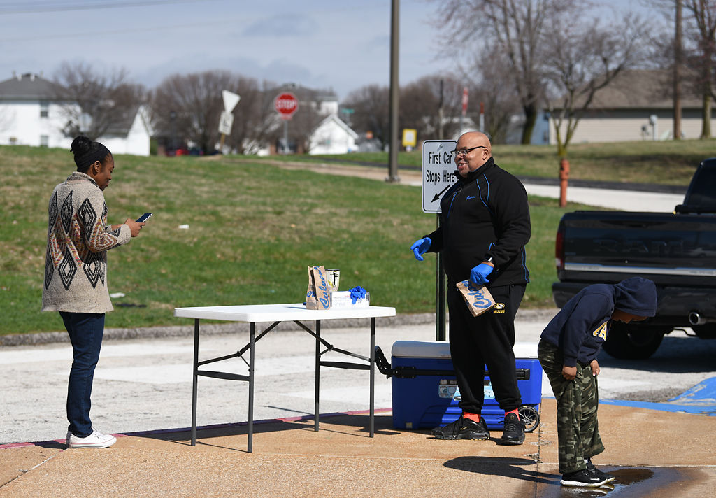 Shaunda Hamilton talks with Rev. James Gray while Keegan Wells plays in a puddle